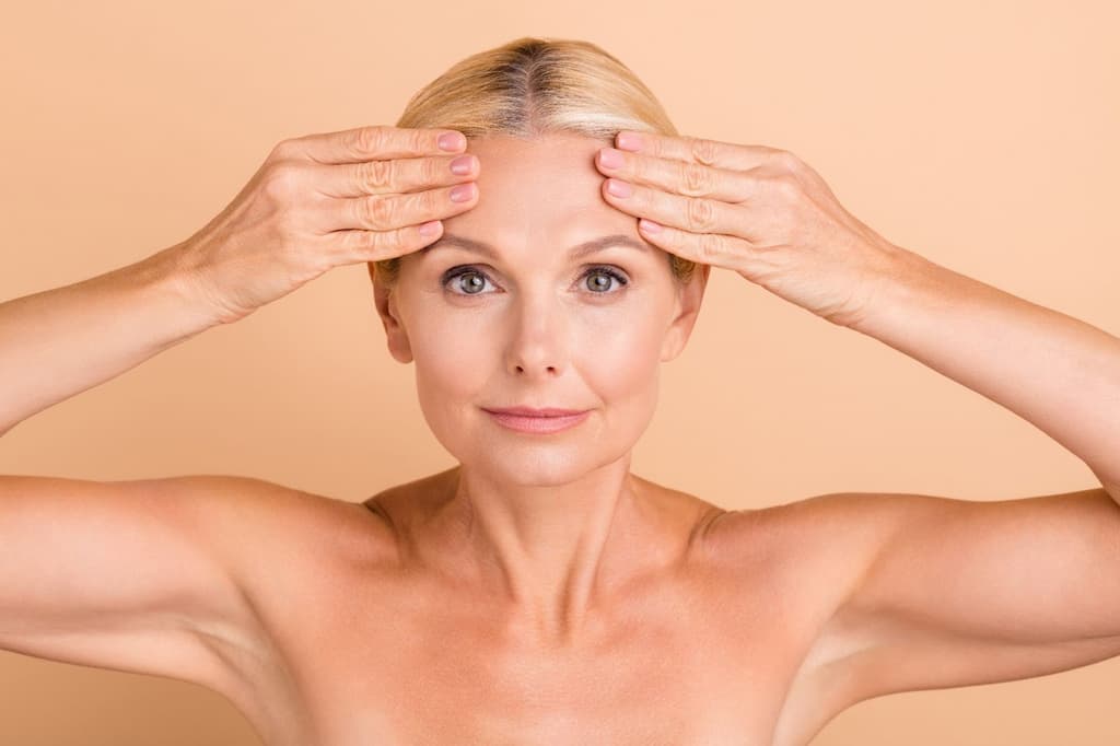 Woman placing both hands on forehead demonstrating forehead lines and expression movements that Botox treats for brow lifting and wrinkle smoothing